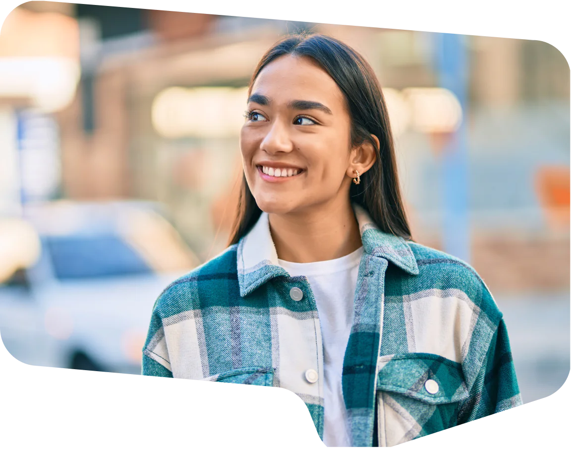 Smiling young woman wearing a plaid jacket with blurred city background